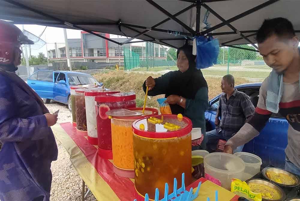 Mohd Fauzi (kanan) yang dibantu ibu bapanya mampu menghabiskan jualan sehingga tiga balang air setiap hari pada musim panas.