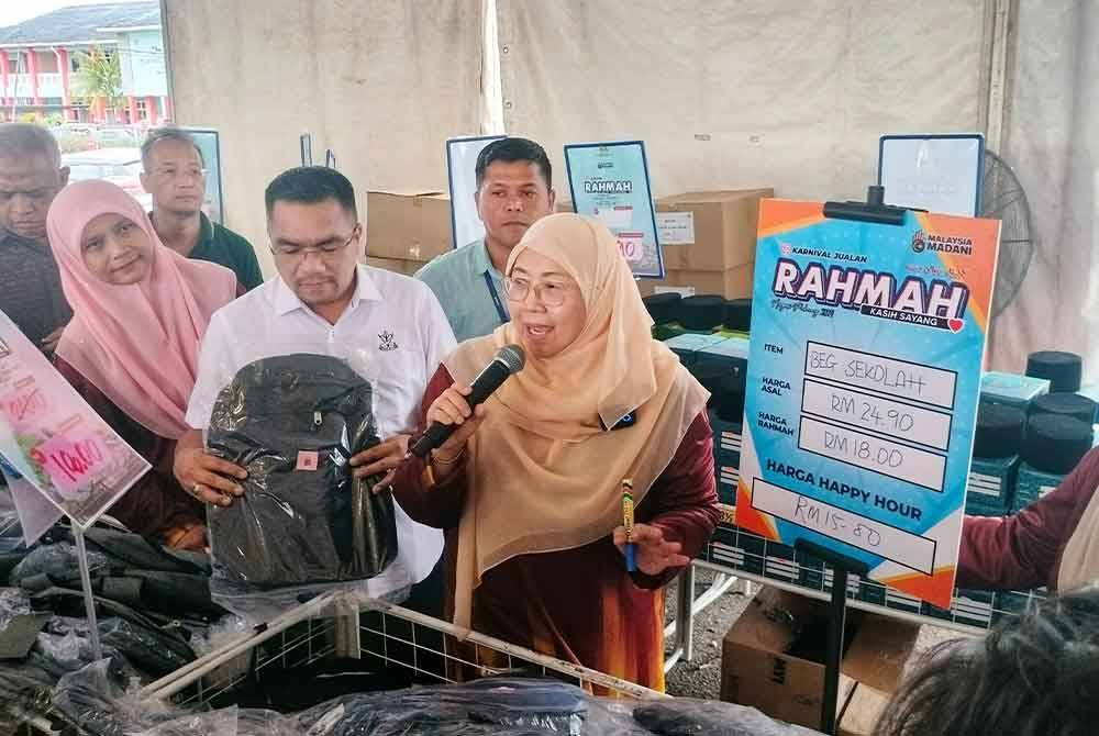Fuziah (dua dari kanan) bersama Amizar (tiga dari kanan) ketika menawarkan harga 'happy hour' untuk beg sekolah bernilai RM15 buat pengunjung karnival pada Ahad.