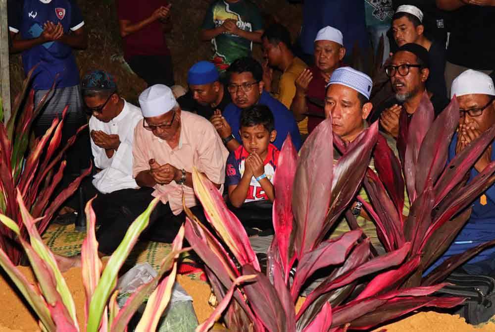 Attar Azim mengaminkan bacaan doa semasa proses pengebumian empat ahli keluarganya di Tanah Perkuburan Islam Felda Trolak Utara dekat Sungkai, malam tadi.