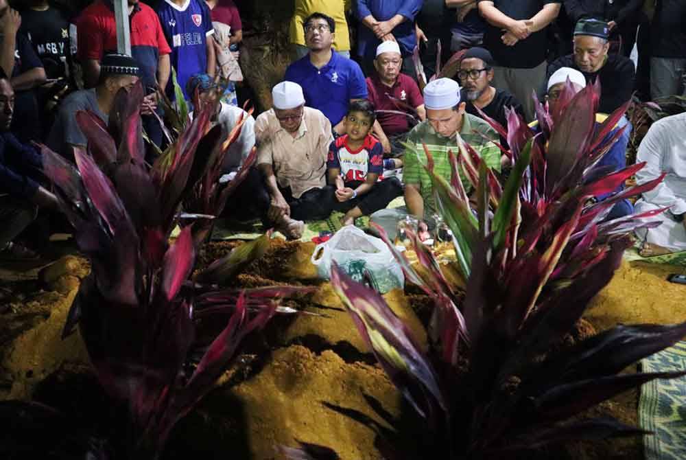 Attar Azim (tengah) merenung sayu pusara empat ahli keluarganya yang terkorban.