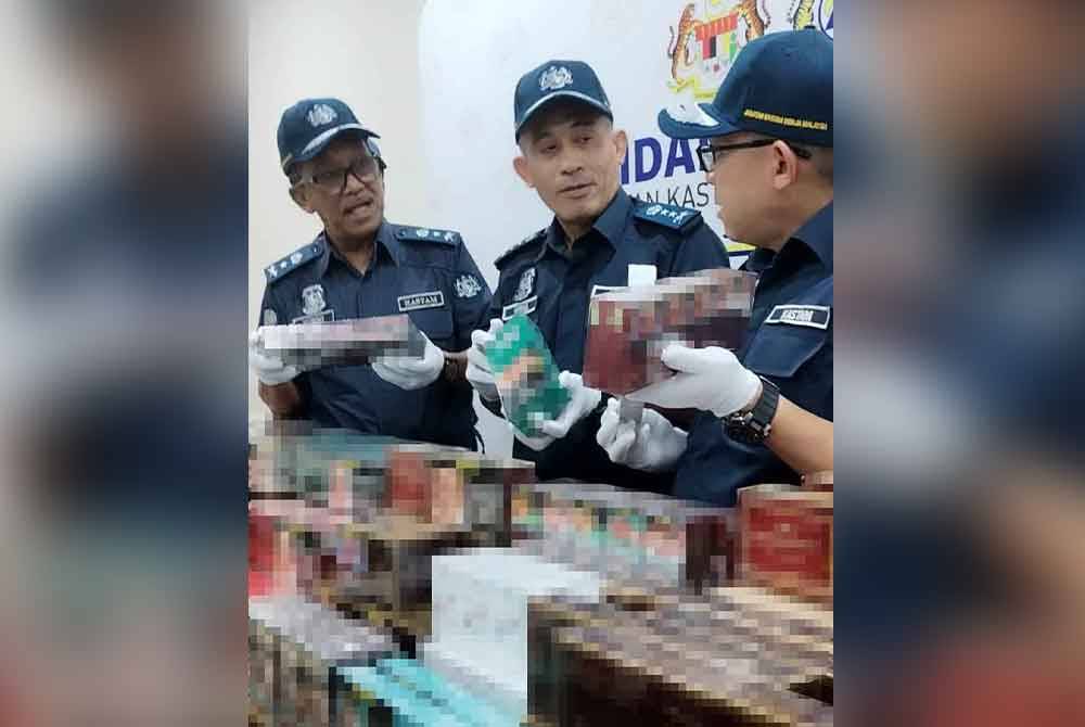 Aminul Izmeer (tengah) bersama sebahagian rokok yang dirampas.