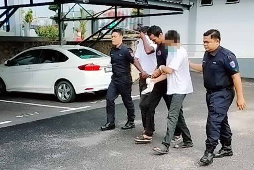 Tertuduh (dua kanan) ketika tiba di pekarangan mahkamah pada Selasa.