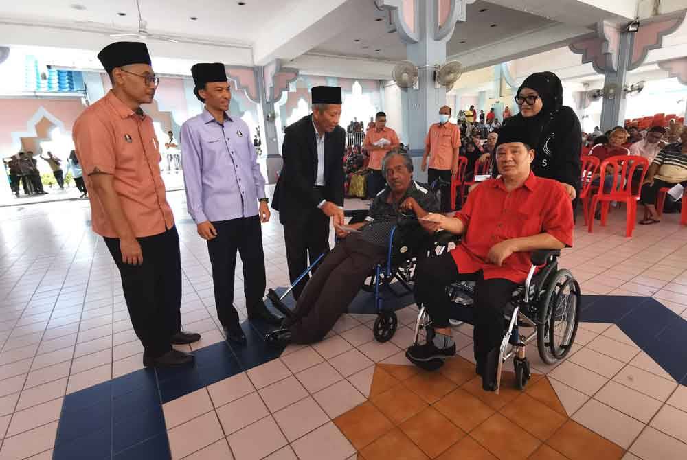 Shaikh Harun (tiga dari kiri) menyerahkan bantuan zakat sempena Ramadan kepada penerima di Dewan Terbuka Jabatan Hal Ehwal Agama Terengganu (JHEAT), Kuala Terengganu pada Selasa.