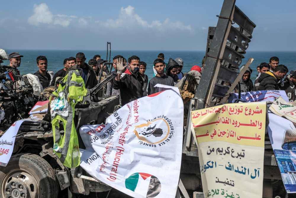 Orang ramai berkumpul di sekeliling trak yang membawa bantuan kemanusiaan yang dilanggar dalam serangan udara Israel dilaporkan di jalan pantai utama di Deir El-Balah di tengah Gaza pada Ahad. Foto AFP
