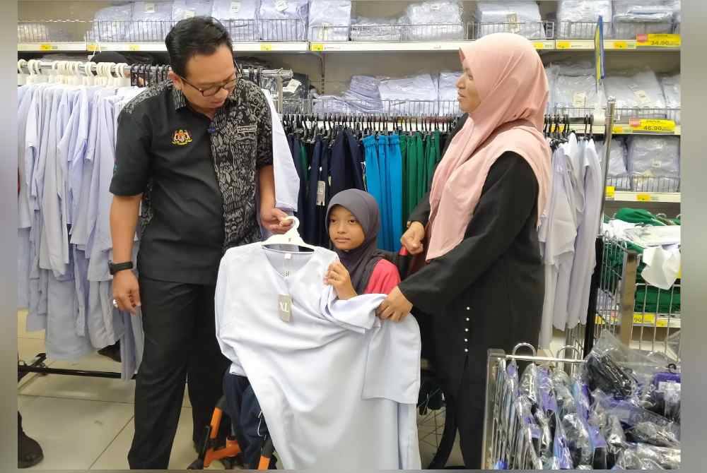 Kamalludin (kiri) menyantuni pelanggan yang membeli barangan kelengkapan persekolahan selepas melancarkan Program Jualan Ihsan Rahmah Kembali Ke Sekolah di Pasar Raya Besar Mydin Meru di sini pada Rabu.