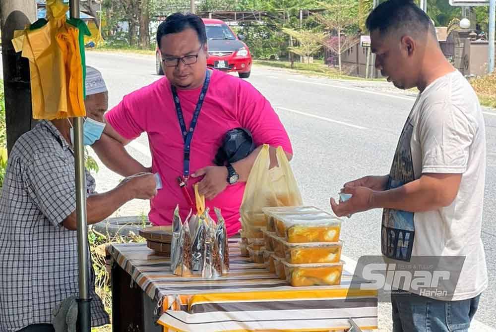 Sabri (kiri) melayan pelanggan yang membeli ikan patin masak tempoyak di gerainya di Kampung Telaga Daing, Kuala Nerus.