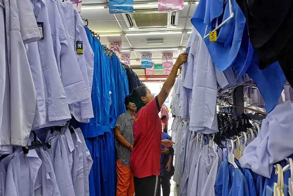 Kelihatan ibu memilih pakai seragam yang sesuai dengan anak mereka di sebuah pasar raya di Taman Tas pada Khamis.