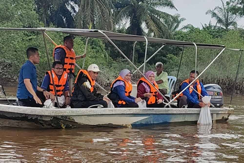 Noraisyah (dua dari kiri) melihat pelepasan benih udang galah pada Program Pemuliharaan Sumber Perikanan Darat Sungai Bernam di Pusat Konservasi Kelip-Kelip Kampung Sungai Panjang, pada Khamis.