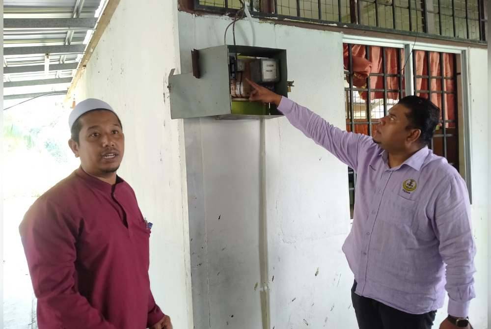 Muhamad Arafat (kanan) menunjukkan fius utama dan wayar yang dipotong individu tidak bertanggungjawab di SRAR Muhammadiah Kampung Ulu Kuang, Chemor di sini pada Khamis.