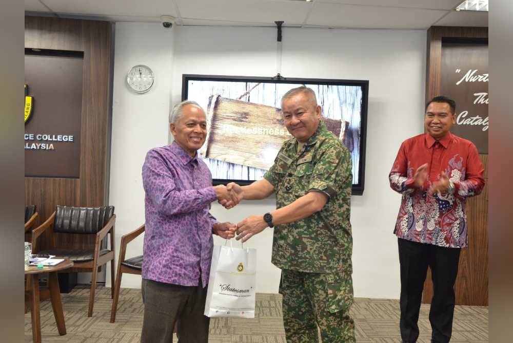 Muhammad Nasir (kiri) menerima cenderahati daripada Johnny selepas sesi perbincangan meja bulat kursus berkenaan di Maktab Ketahanan Nasional di Putrajaya pada Khamis.