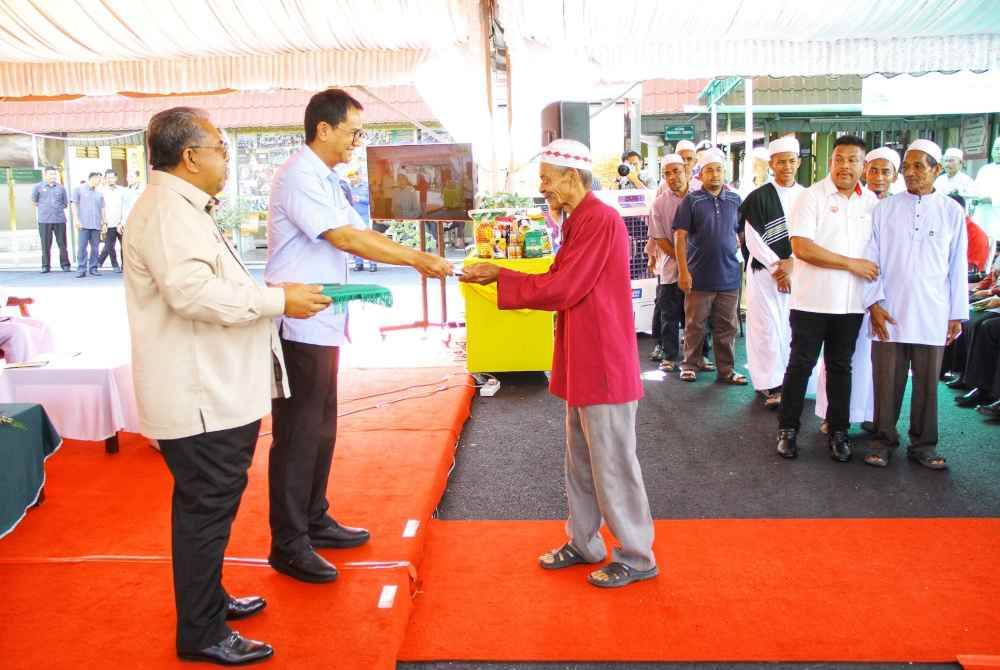 Tengku Sarafudin mengagihkan sumbangan fidyah kepada penerima pada Majlis Kurniaan Keluarga Diraja Sultan Negeri Kedah dan Penyampaian Sumbangan Fidyah bagi Tahun 1445H/2024M pada Khamis..