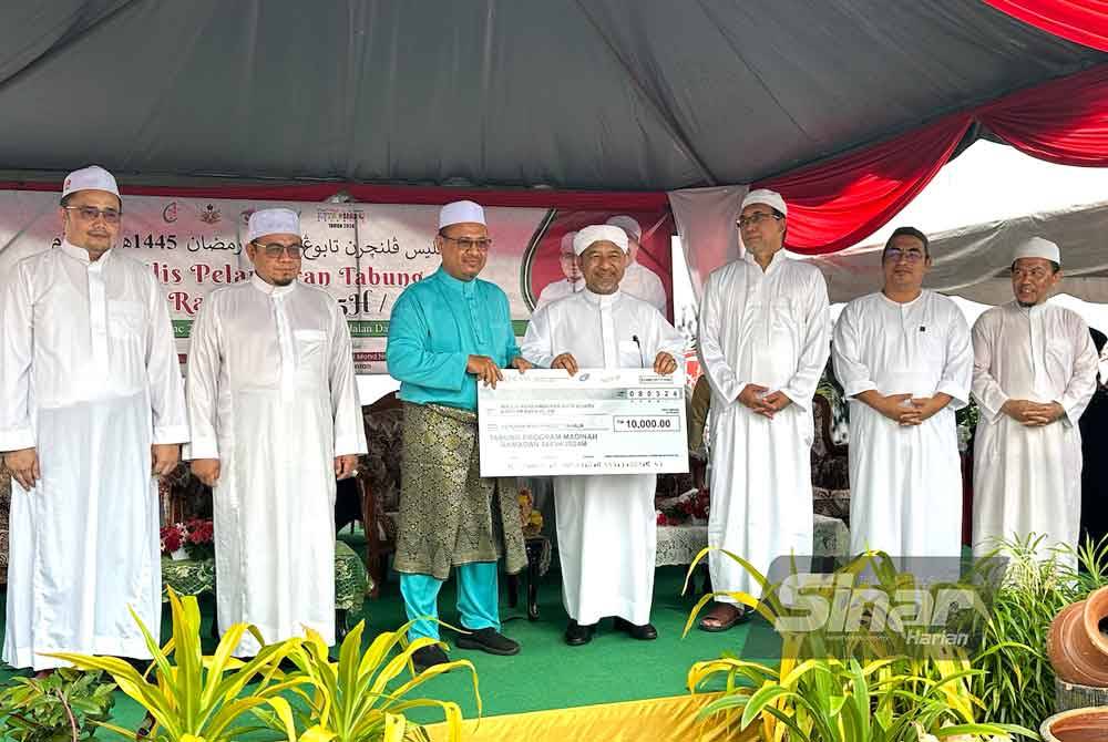Mohd Nassuruddin (tengah) menerima sumbangan RM10,000 yang diberikan oleh Rumah Ngaji Kelantan untuk Tabung Madinah Ramadan.