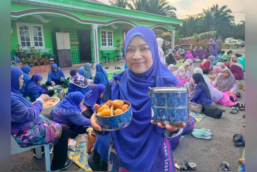 Misliah menunjukkan mangkuk tingkat berisi juadah yang dimasak sendiri untuk dinikmati bersama penduduk lain.