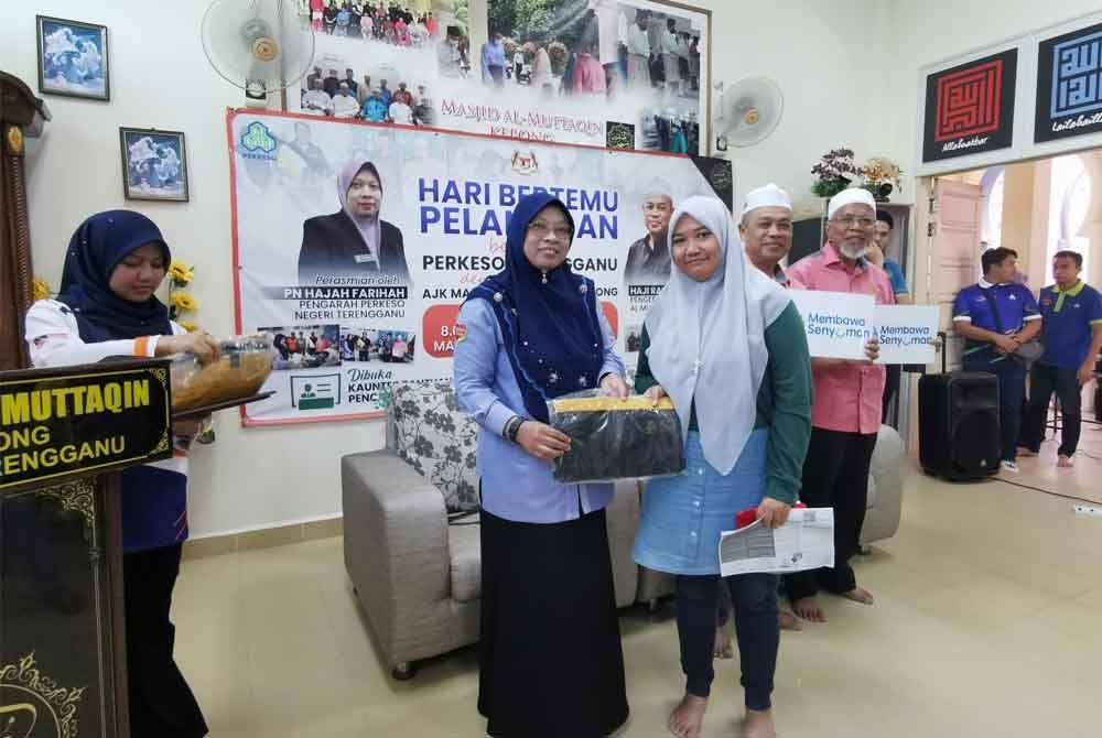 Farihah (dua dari kiri) menyampaikan cenderahati kepada pengunjung terawal mendaftar caruman pada program khidmat komuniti bersama agensi di Masjid Al-Muttaqin.