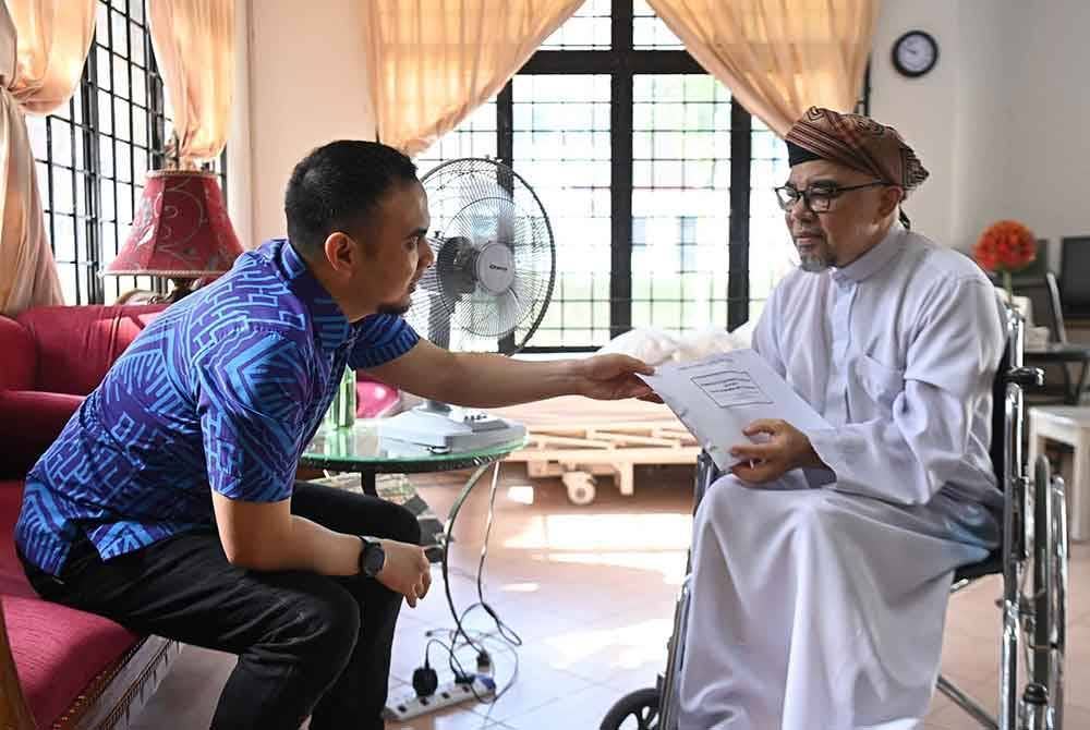 Ahmad Farhan (kiri) menyampaikan sumbangan daripada pihak Anwar kepada Sheqal yang kini berkerusi roda akibat menderita serangan strok. Foto: Facebook Anwar Ibrahim