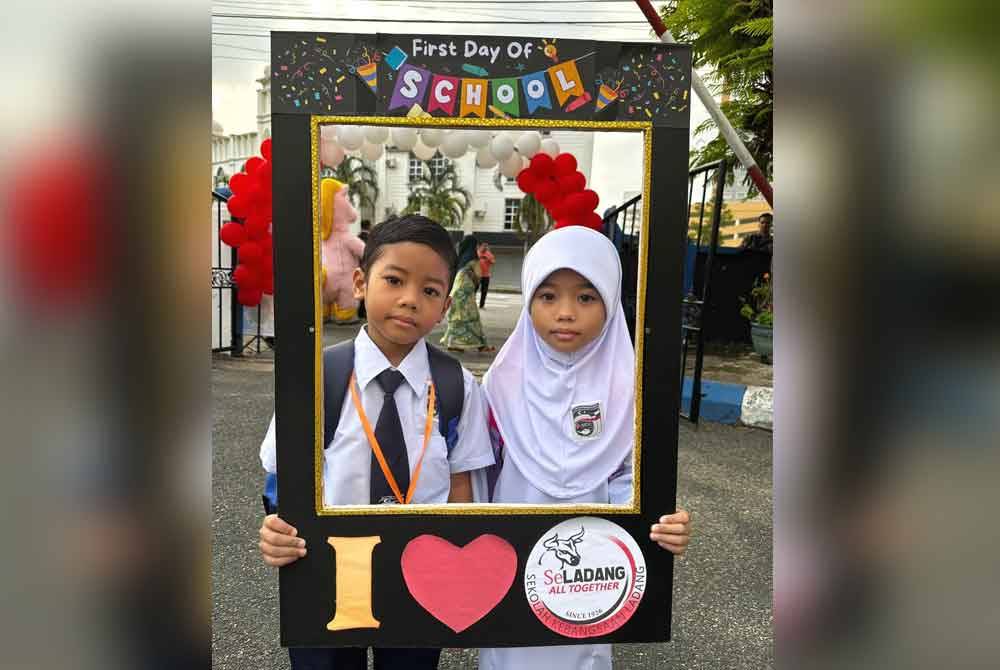 Dua beradik yang bersekolah di Sekolah Kebangsaan (SK) Ladang merakam gambar pada hari pertama sesi persekolahan 2024/2025.