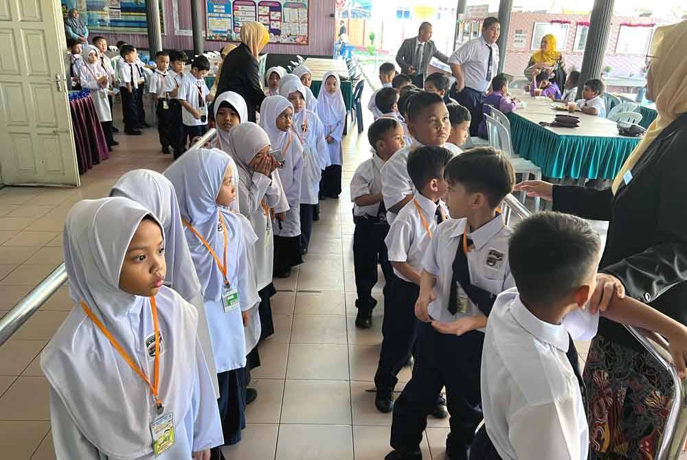 Murid Tahun Satu dibantu untuk ke kantin sekolah ketika tinjauan di Sekolah Kebangsaan (SK) Ladang di Kuala Terengganu.