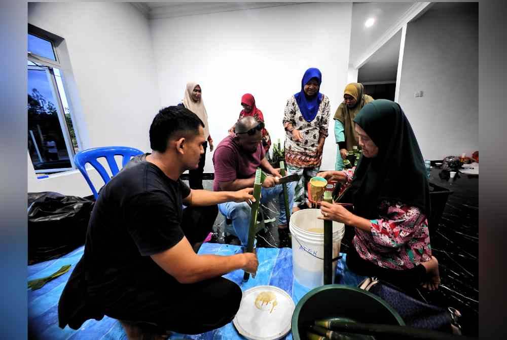 Anak muda bergotong-royong membuat lemang sambil dibantu golongan lebih tua.