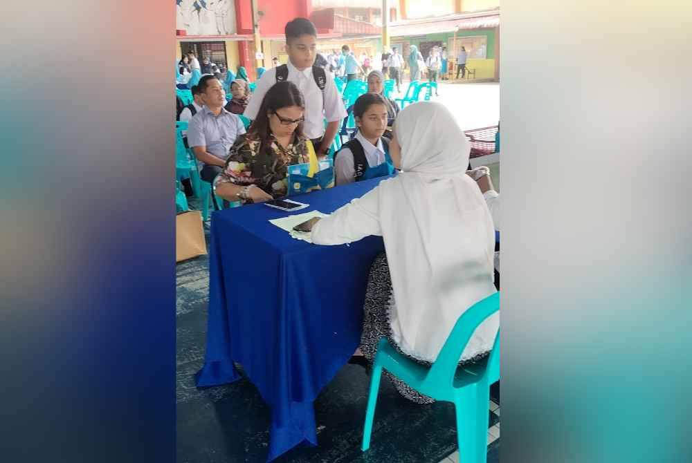 Pelajar-pelajar melakukan pendaftaran di hari pertama persekolahan di SMK Sultan Ismail di Johor Bahru pada Ahad.