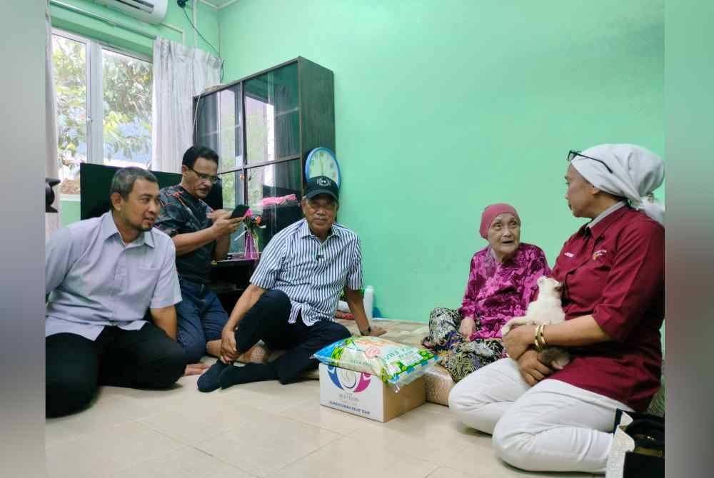 Muhyiddin (dua dari kiri) menyantuni warga emas, Jemah Kassim, 91 pada program Ziarah Kasih Ramadan di Pekan Pagoh pada Ahad.