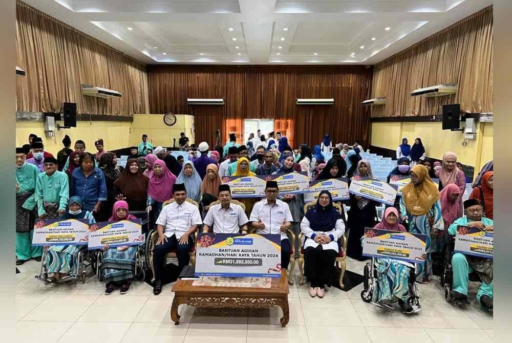 Penerima bantuan bergambar bersama pegawai LZS pada program simbolik bantuan Ramadan dan Hari Raya LZS di Kem Bumi Jati, Jalan Kebun pada Ahad.