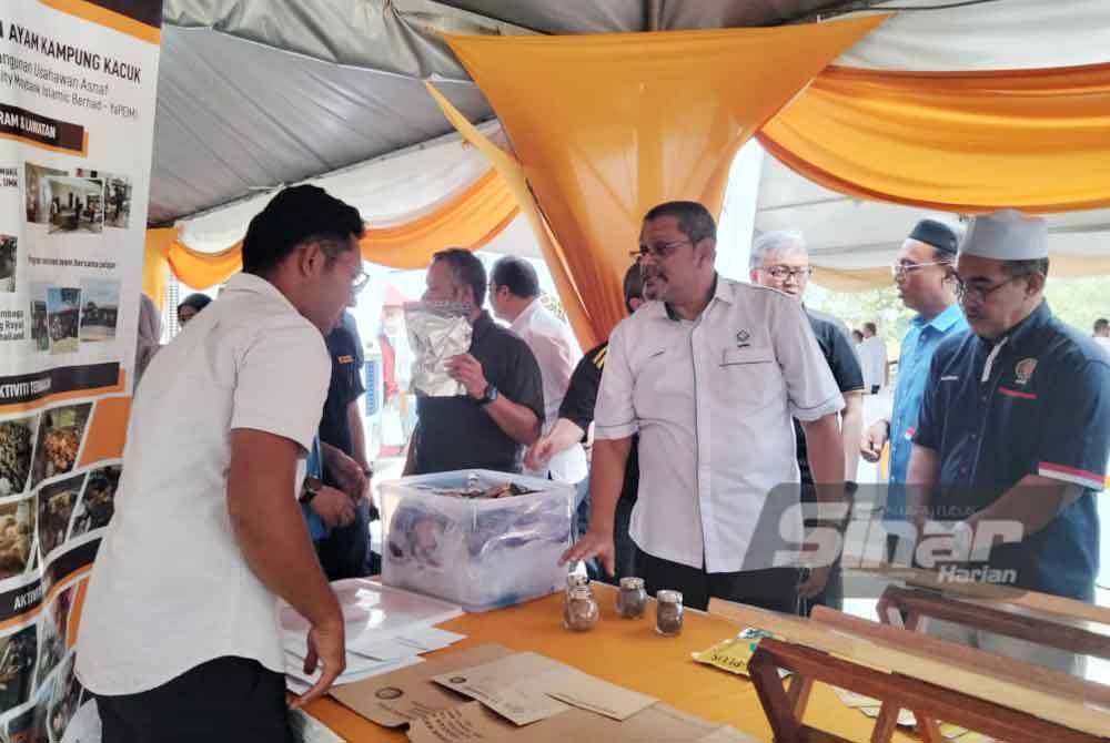 Ameer Ali (tengah) melihat proses penghasilan ayam kampung kacuk di reruai sempena Majlis Peluncuran Program Pembangunan Usahawan Asnaf (Inspirasipreneur Community Maybank-YaPEIM) pada Ahad.