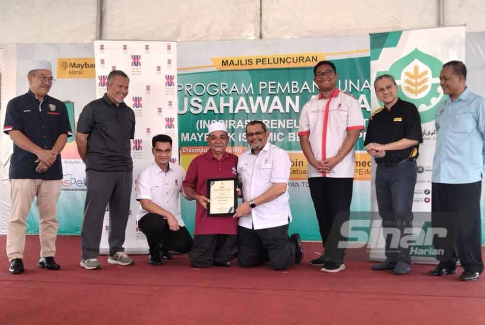 Ameer Ali (empat, kanan) menyampaikan sijil kepada peserta penternak ayam kampung kacuk sempena Majlis Peluncuran Program Pembangunan Usahawan Asnaf (Inspirasipreneur Community Maybank-YaPEIM) pada Ahad.