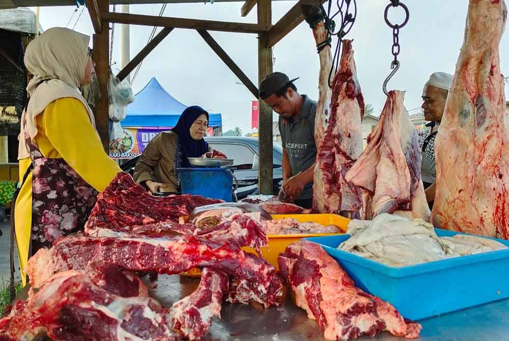 Muhd Shahrulrazi melayan pelanggannya yang membeli daging lembu tempatan di gerainya yang terletak di Kampung Chica dekat sini. - Foto: Bernama