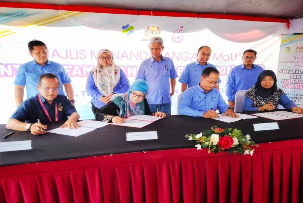 Jaffri (duduk, kiri) menandatangani MoU antara FAMA dan Ayam Bismi sambil diperhatikan Aminuddin (berdiri, tengah).