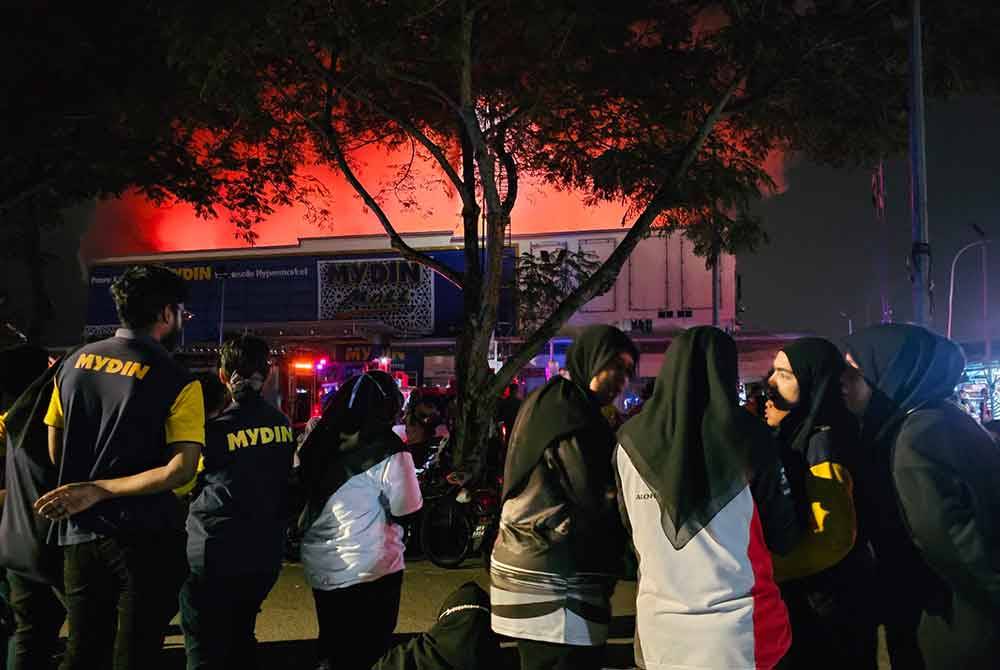 Pekerja dan pengunjung melihat kebakaran bangunan pasar raya di Manjoi pada Ahad.