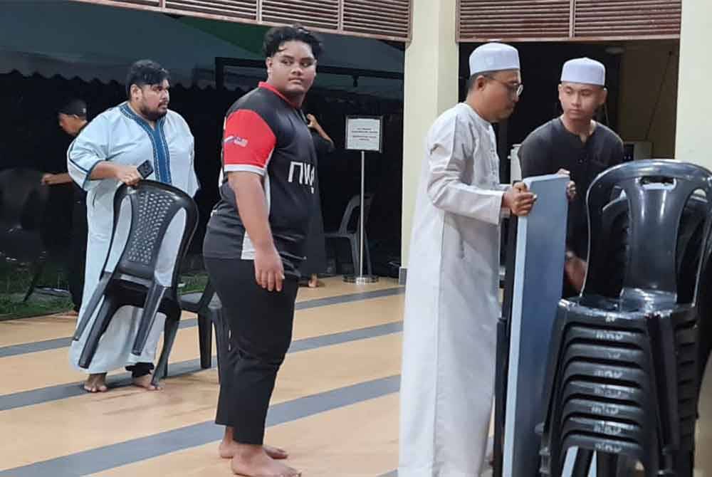 Ahli jawatankuasa masjid mengemas ruang makan untuk dijadikan tempat solat.