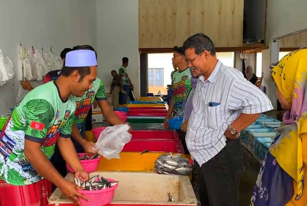 Zuhairi (kiri) melayan pelanggan yang datang ke kedainya yang terletak di bandar utama Gua Musang.