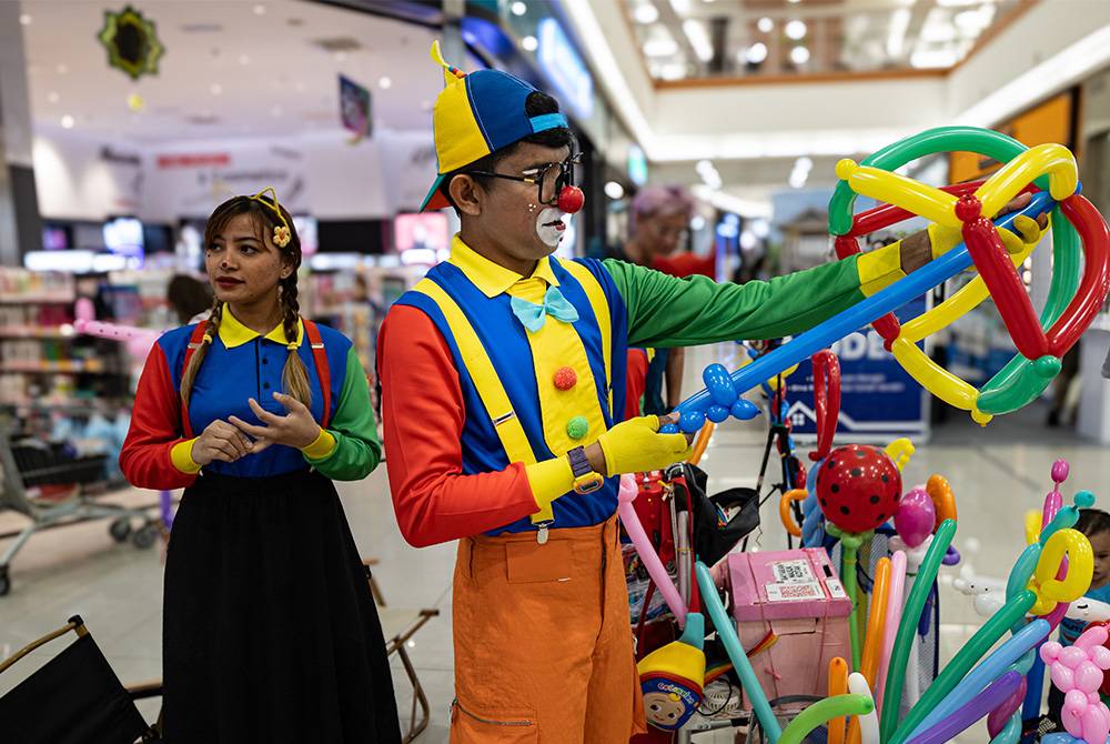 Gelagat badut Muhammad Al-Hazim Ahmad, 32, (Jiji) (tengah) membentuk belon sewaktu menyantuni pelanggannya ketika ditemui BERNAMA baru-baru ini.