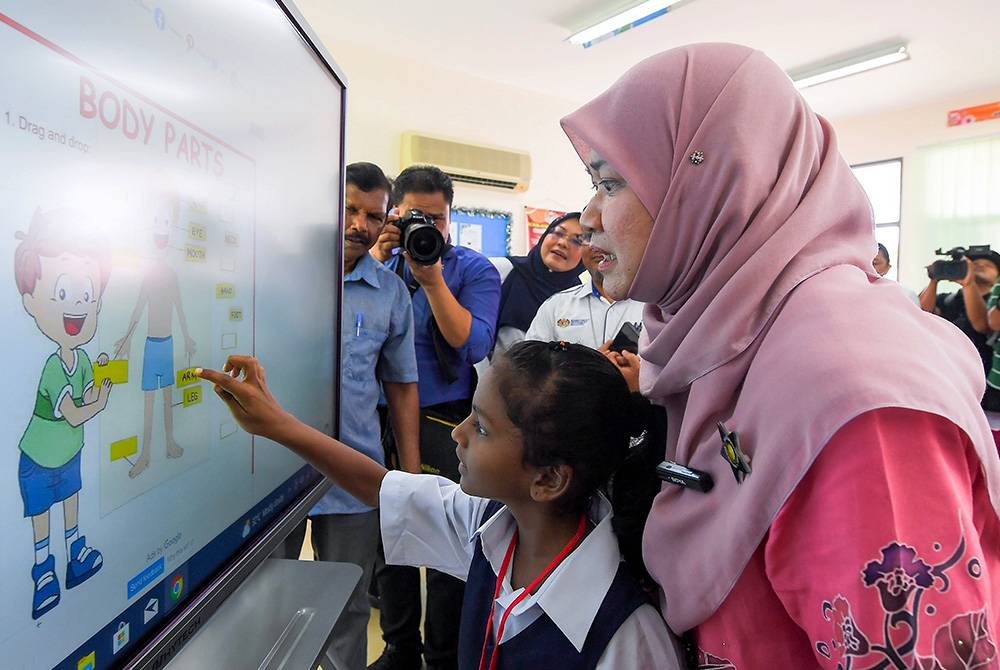 Fadhlina membantu seorang murid ketika lawatan kerja sempena pengoperasian sekolah sesi 2024/2025 di SJKT Ladang Sagga di Port Dickson pada Selasa.
