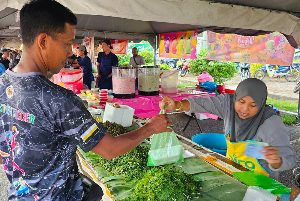 Seorang pengunjung membeli makanan tradisional pecal yang dijual di Bazar Ramadan Stadium Perak.