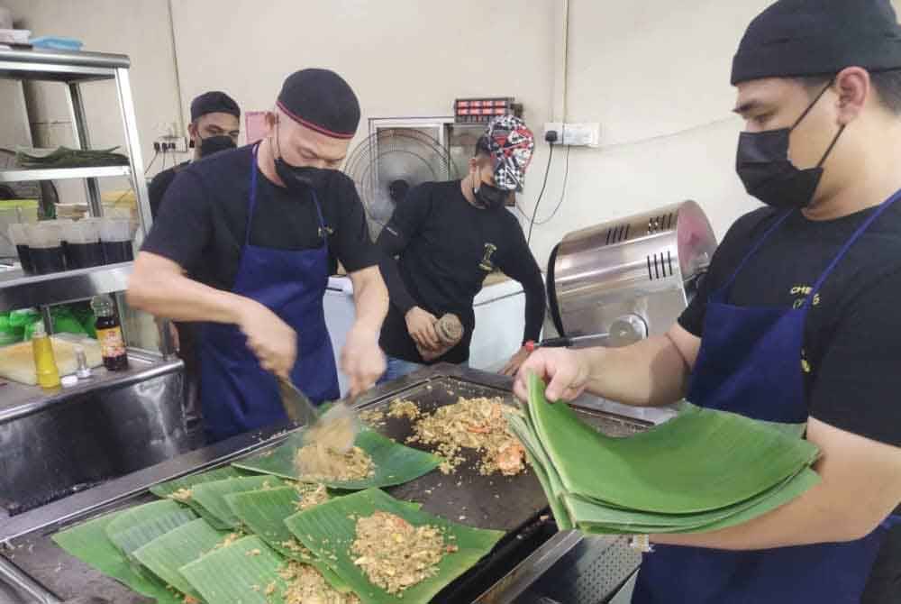 Nasi goreng yang siap dimasak disusun ke dalam daun pisang sebelum dibungkus untuk dihidangkan.