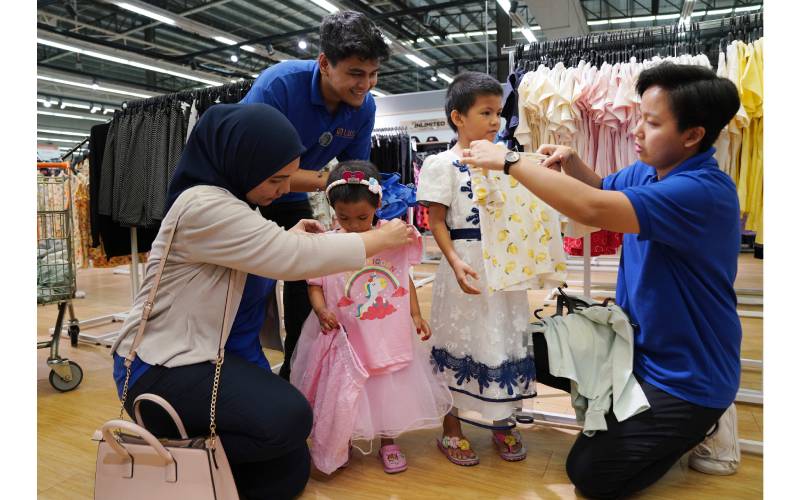 Kakitangan LBS melayani Siti Salwa (dua dari kanan) dan Nur Aleeya Damia mencuba baju raya.
