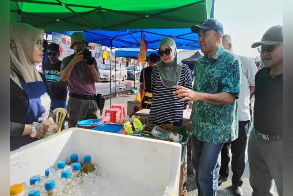 Mohd Jafni (dua, kanan) berkata sesuatu kepada peniaga Bazar Ramadan, Bandar Baru UDA ketika melawat kawasan berkenaan pada Selasa.