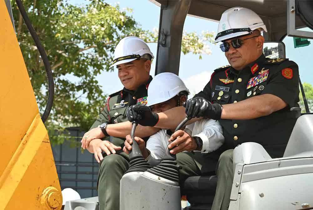 Muhammad Hafizuddeain (kanan) mengendalikan jengkaut sebagai menyempurnakan gimik Majlis Pecah Tanah Projek Pembinaan Masjid Baharu 2 Briged di Batalion Kedua Rejimen Renjer Diraja, Kem Syed Putra pada Rabu.
