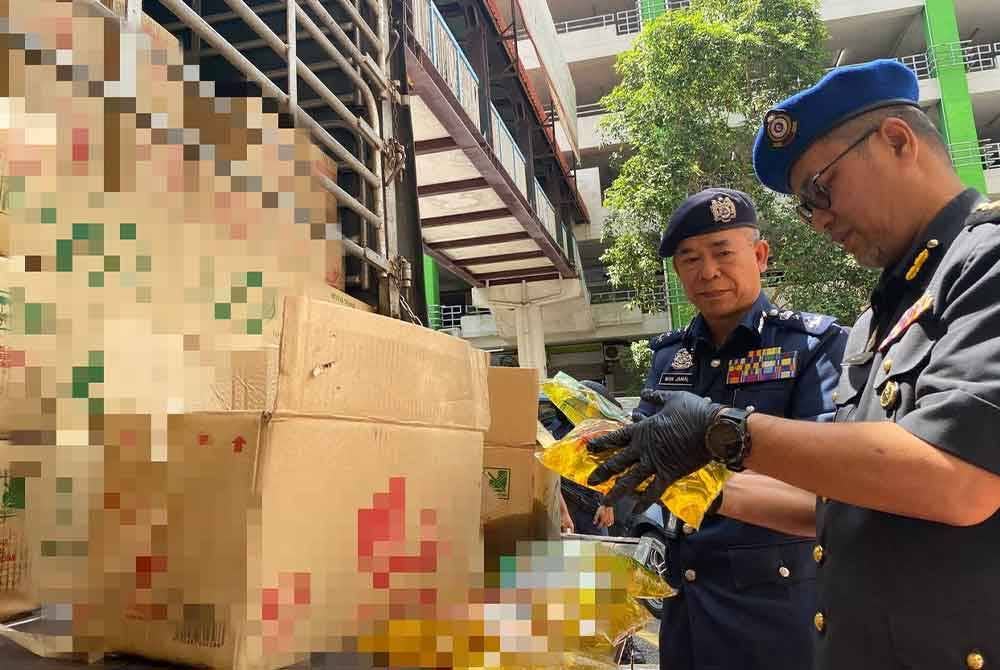 Azman (kanan) memeriksa minyak masak peket bersubsidi yang dirampas dan dipercayai akan diseludup ke negara jiran melalui pangkalan haram di Sungai Golok.