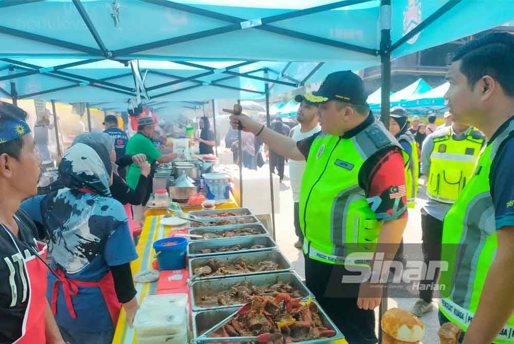 Ariffin (tengah) memberi penjelasan kepada peniaga bazar Ramadan di Taman Tun Dr Ismail (TTDI), Kuala Lumpur semasa pemeriksaan dijalankan KPDN Kuala Lumpur pada Rabu. Foto Hisyamuddin Ayub