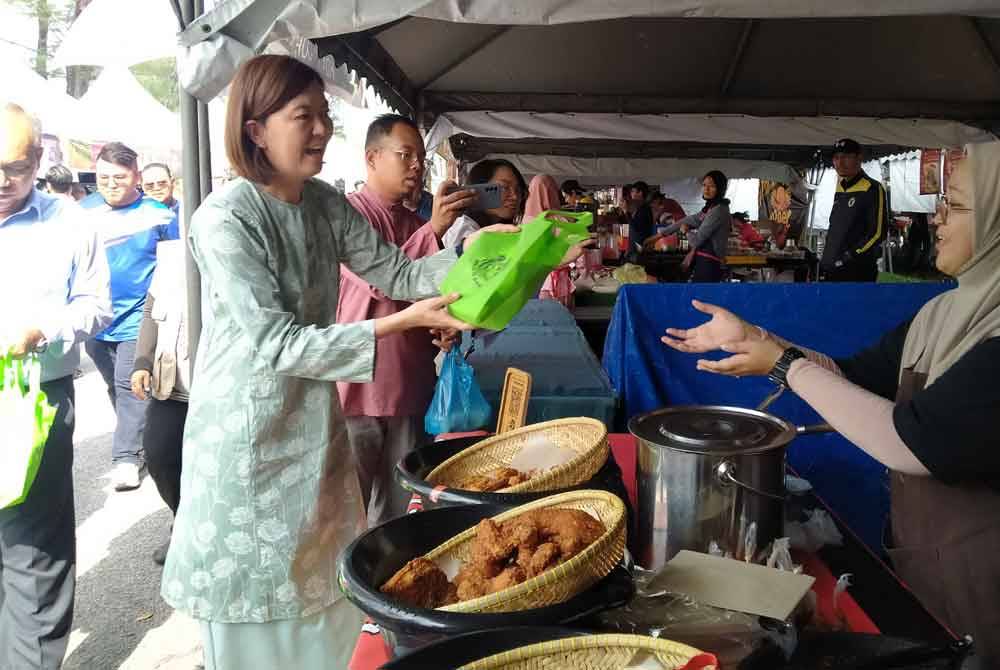 Sandrea (kiri) menyampaikan apron kepada peniaga di Bazar Ramadan Stadium Perak di sini pada Rabu.