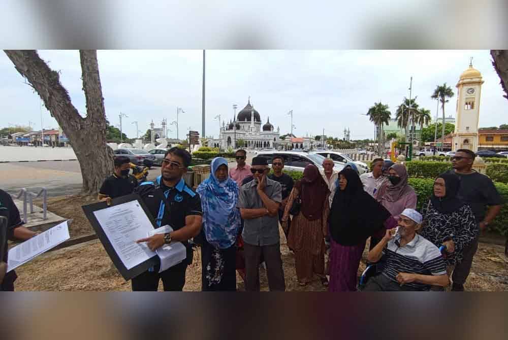 Hishamuddin (kiri) memberi penerangan kepada penduduk sebelum menyerahkan surat memohon ulasan berkenaan tanah rizab Melayu kepada Pejabat Tanah dan Galian (PTG) Kedah, pada Rabu.