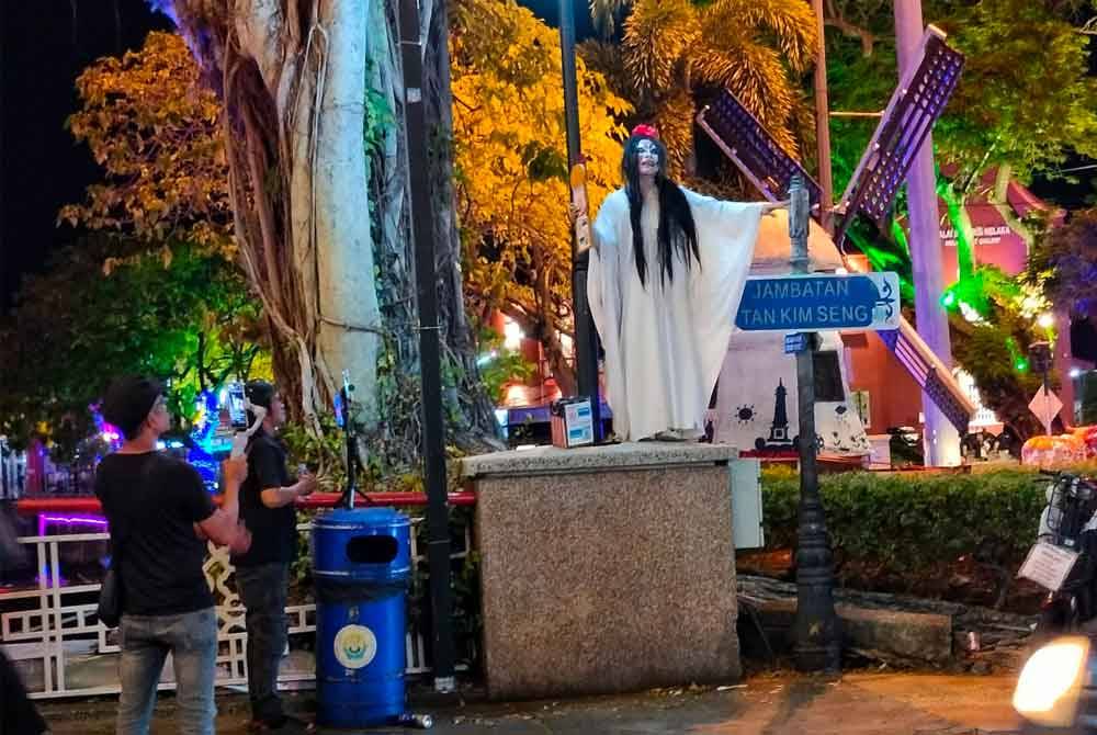 Mohd Saifen memakai kostum pontianak dan menghiburkan orang ramai yang lalu lalang di Jalan Jonker, Banda Hilir.