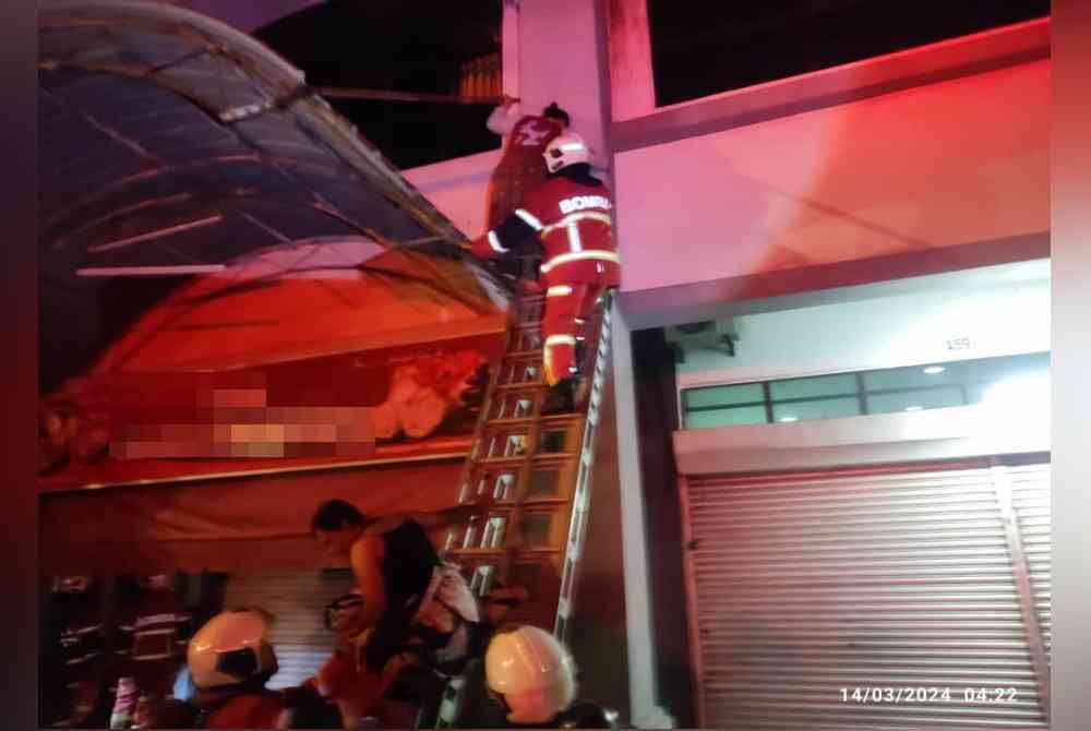 Anggota bomba membantu membawa turun mangsa yang terperangkap menggunakan tangga jentera selepas bangunan rumah kedai tiga tingkat di Jalan IM3/11, Bandar Indera Mahkota di sini terbakar awal pagi Khamis.