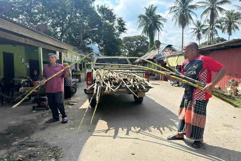 Wan Mohd Zulhilmi (kanan) mengambil bekalan tebu daripada penduduk tempatan.