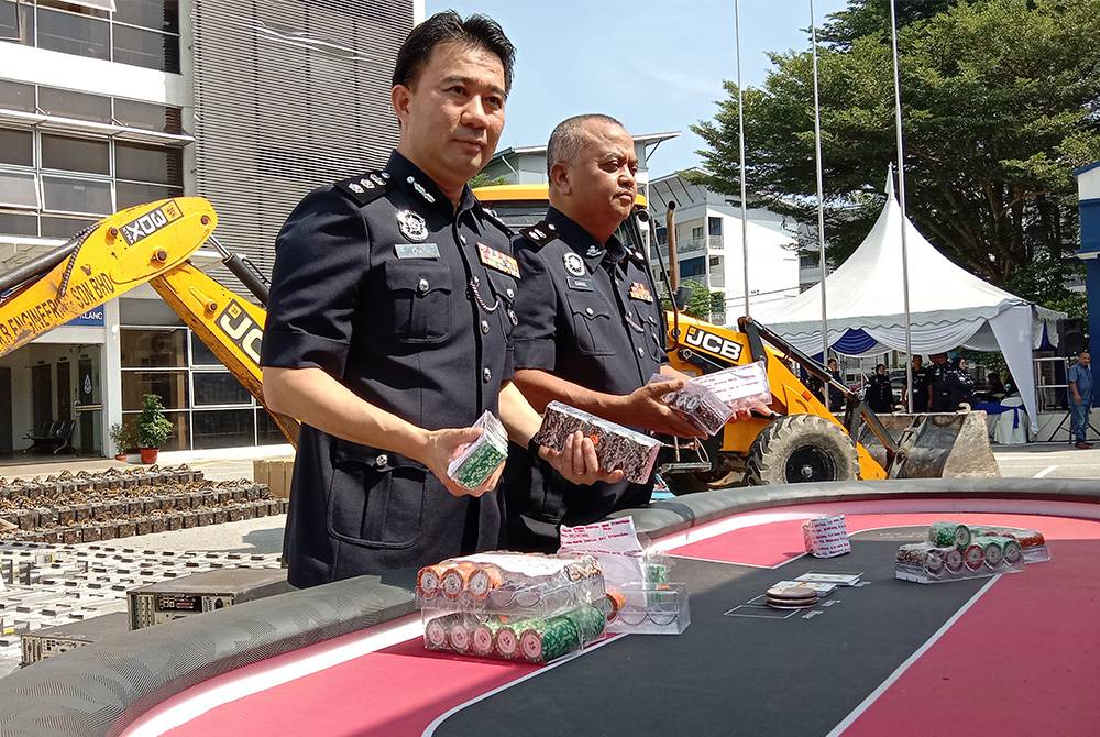 Hoong Fong (kiri) menunjukkan antara peralatan dirampas dalam Majlis Pelupusan Barang Kes dekat IPD Klang Selatan, pada Khamis.