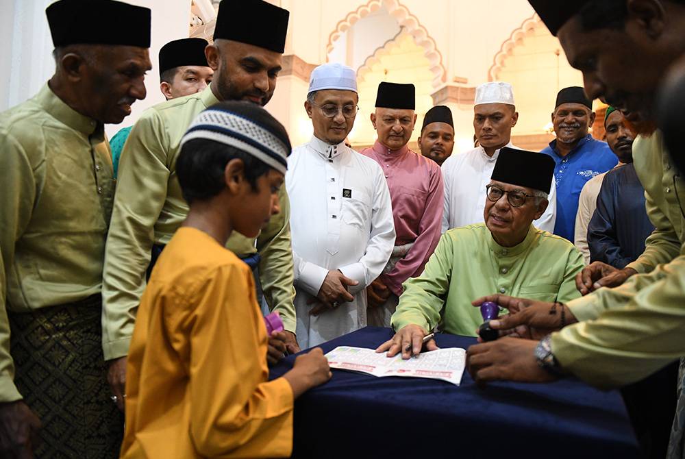 Yang Dipertua Negeri Pulau Pinang, Tun Ahmad Fuzi Abdul Razak menandatangani buku khas Program Didik Kanak-kanak untuk jemaah cilik sempena Ramadan selepas selesai solat tarawih di Masjid Kapitan Keling malam kelmarin. - Foto Bernama