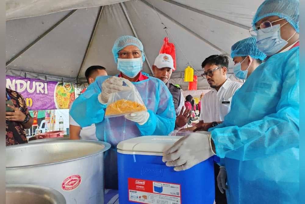 Sivanesan (kiri) menunjukkan sampel makanan yang diambil dari gerai di Bazar Ramadan Stadium Perak di Ipoh sempena Majlis Pelancaran Operasi Keselamatan Makanan Sempena Bulan Ramadan Peringkat Negeri Perak.