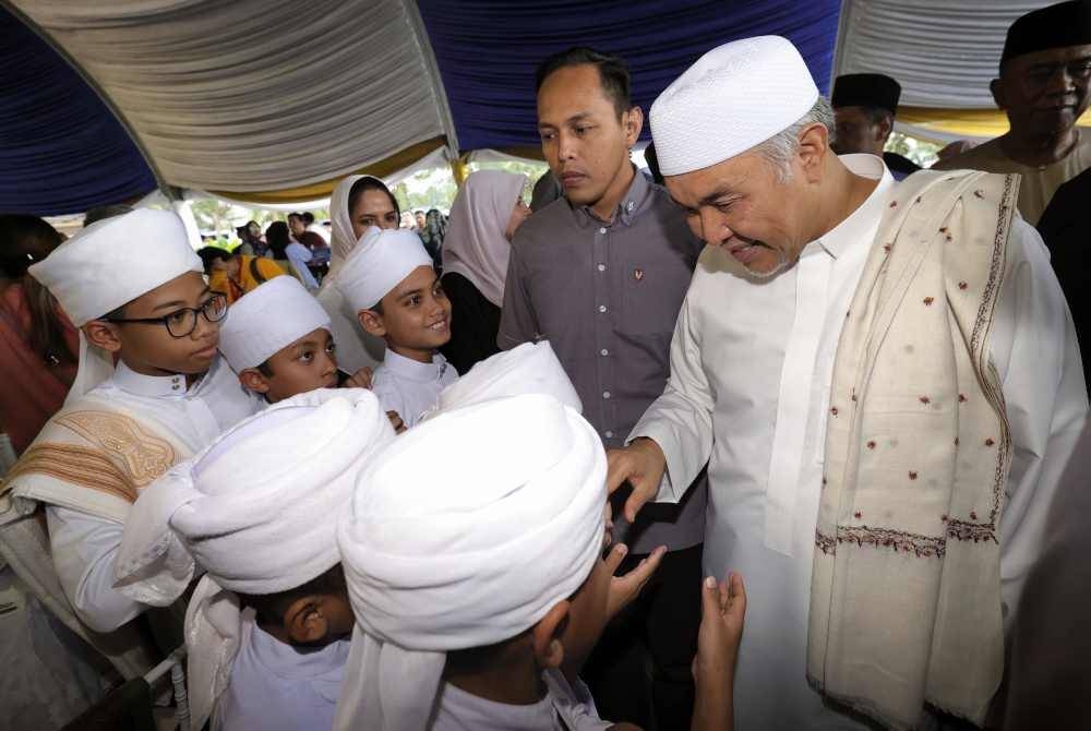 Ahmad Zahid (kanan) bersalaman dengan murid tahfiz ketika menghadiri Majlis Santunan Kasih Ramadhan 1445H di pekarangan Masjid Jamek Pekan Layang-Layang, Simpang Renggam hari ini. Foto Bernama